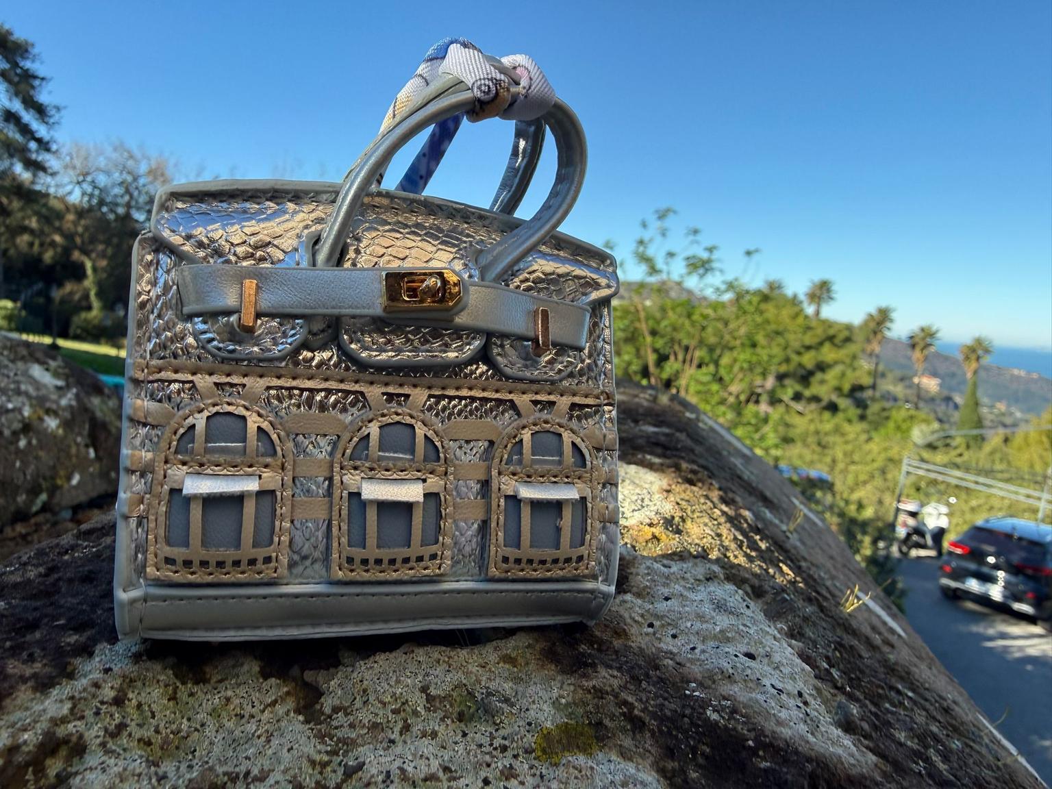 Caryina mini facade bag charm in silver, styled against a neutral backdrop.